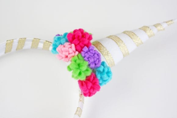 Glued the mini pompom flowers around the base of the horn | CatchMyParty.com
