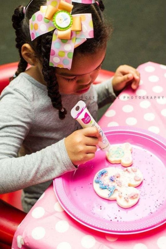 Little girl decorating Minnie Mouse cookies