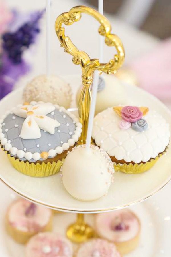 The delicate mix of cupcakes, some decorated with fondant bows, others with pretty flowers at a Parisian Mother's Day tea party