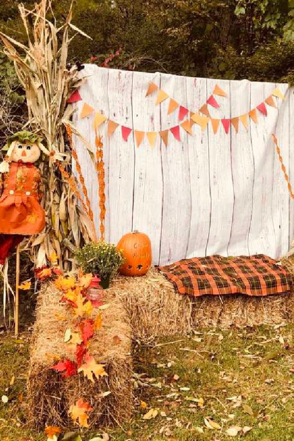 Fall harvest-inspired photo booth props with haystacks and a scarecrow