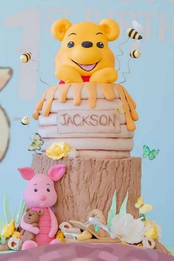 Pooh bear in a honey pot on a log tiered birthday cake
